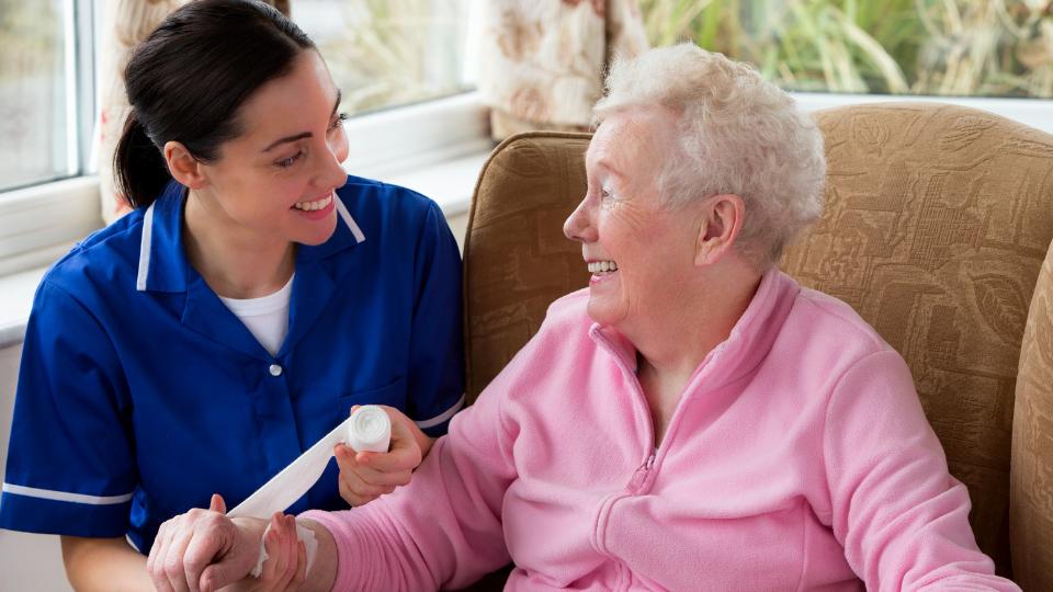 a nurse bandaging a elderly person in a care home