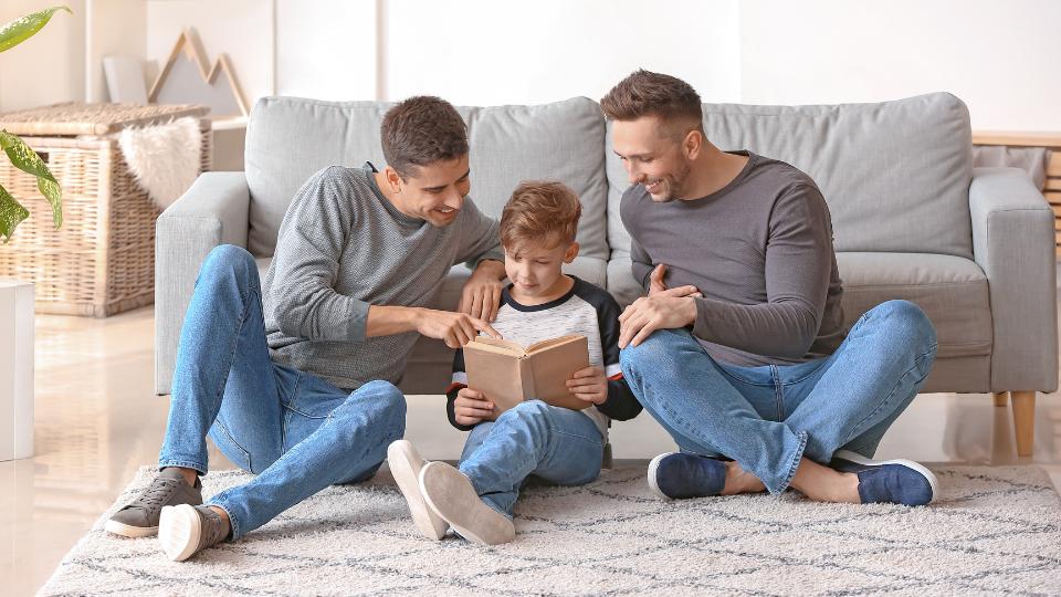An LGBT male couple reading a book with their son