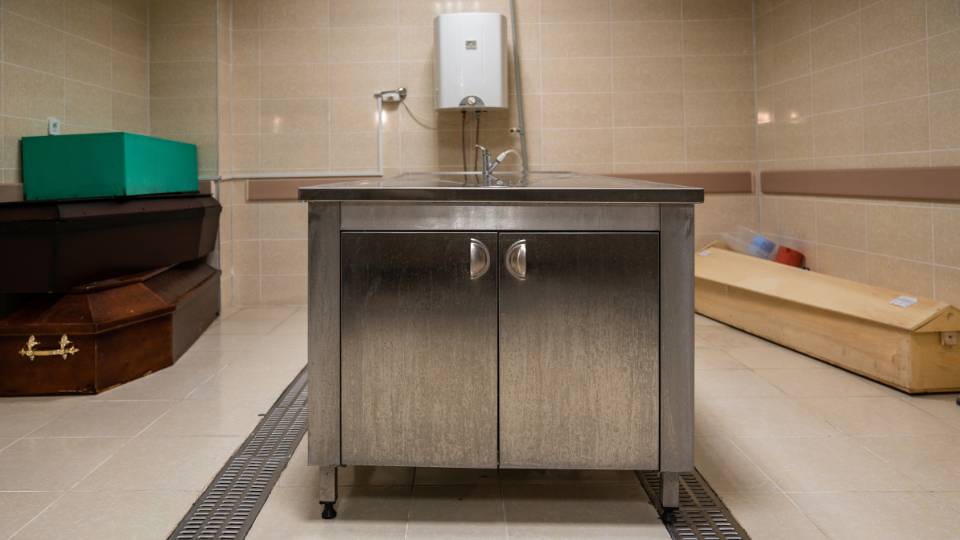 A morgue in a funeral home with coffins in the background
