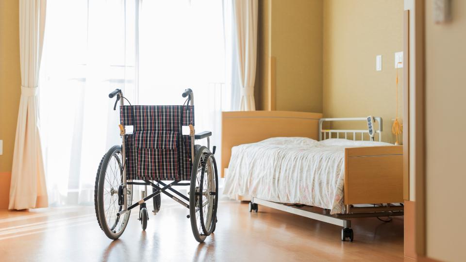 a care home bedroom with a wheelchair and a bed
