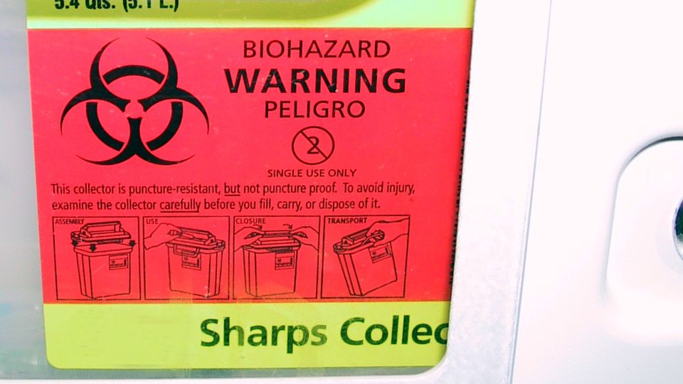 Biohazard label in a sharps waste collection bin.