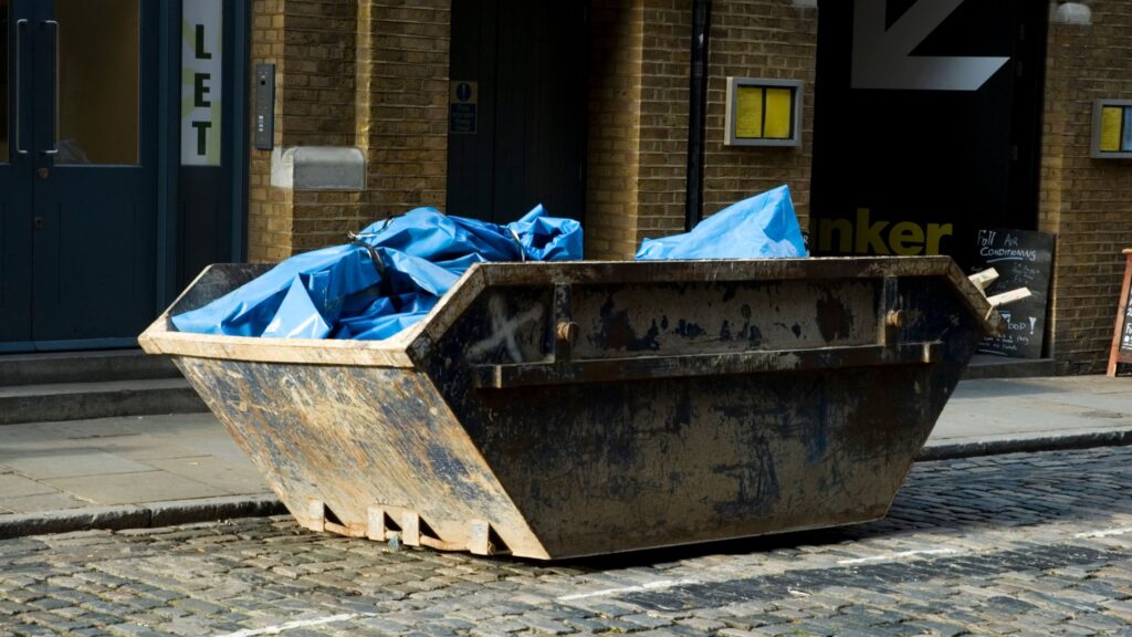 filled skip on side of road