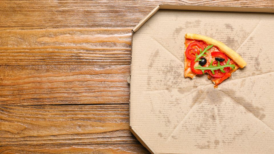 Leftover pizza and greasy pizza box.